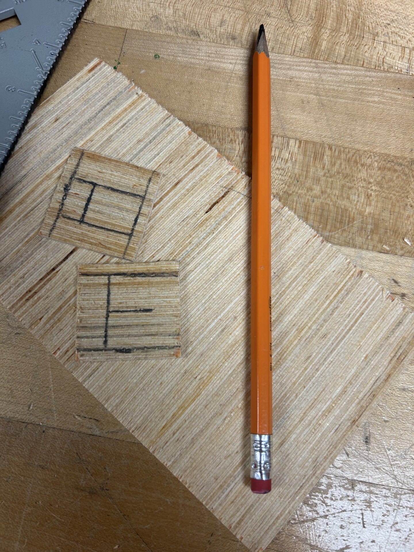 Marked plywood bracket details beside a pencil